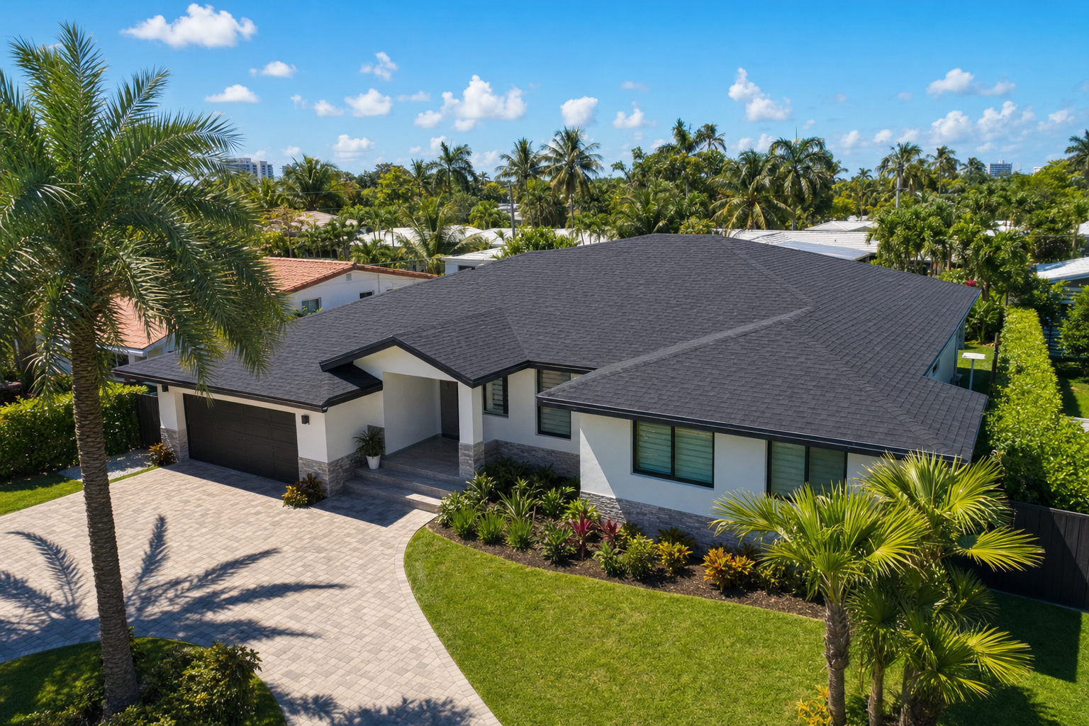 45-degree drone photo of a completed dark architectural shingle roof on a South Florida ranch home in Fort Lauderdale, clean driveway, bright blue sky, palm trees, finished-project reveal, no people, no text